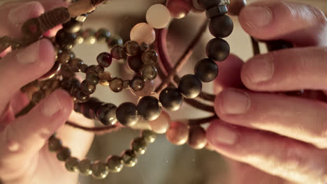detailed view of hand-held beaded bracelets and reflection