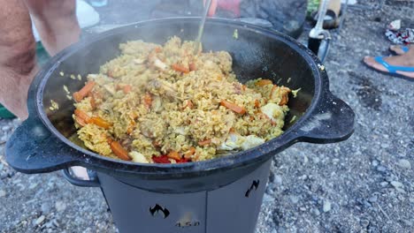 a large pot of pilaf is being stirred with a wooden spoon