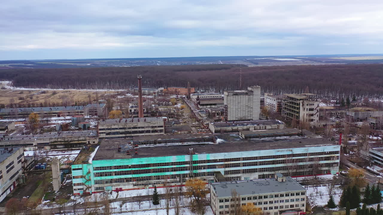 Old ruined industrial plant. Abandoned place with ruined buildings on nature background. Camera rising. Aerial view.