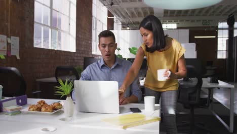 diversos colegas de negocios masculinos y femeninos en una discusión en el trabajo usando una computadora portátil