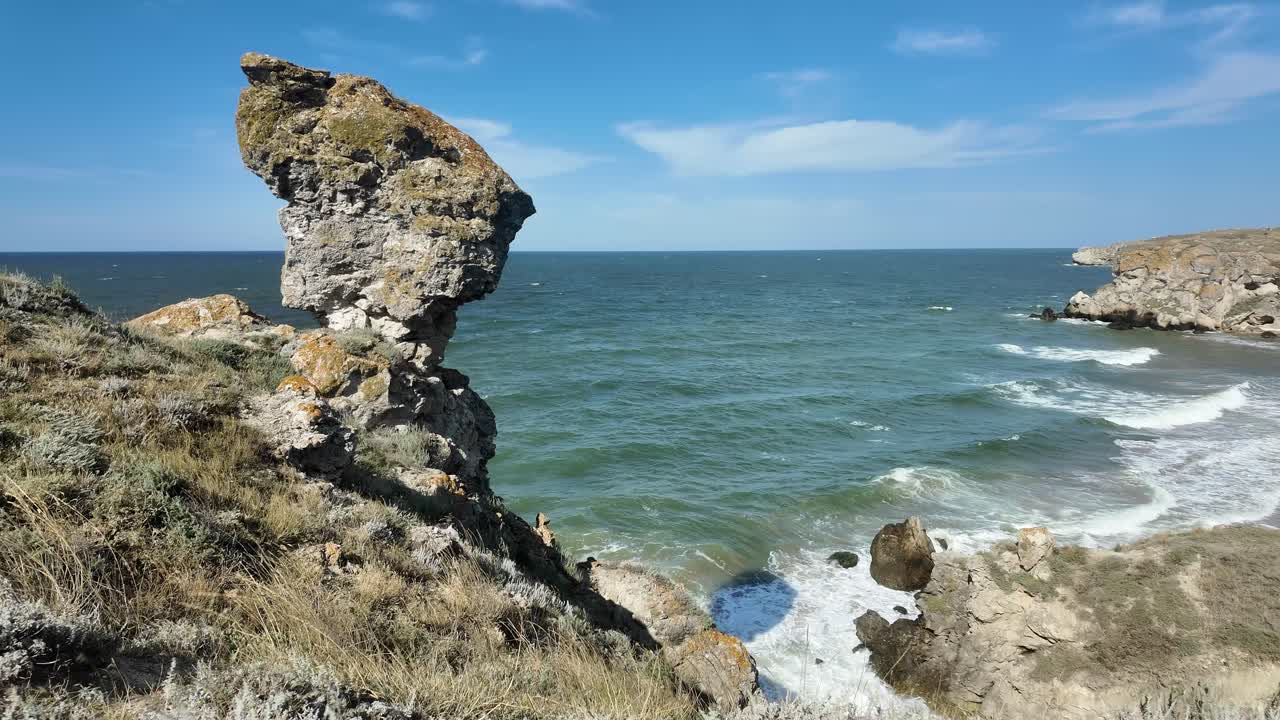 크리미아의 독특한 자연구조가 은 파란 하늘을 배경으로 서있는 바위 해안에 파도가 부히고 있습니다.