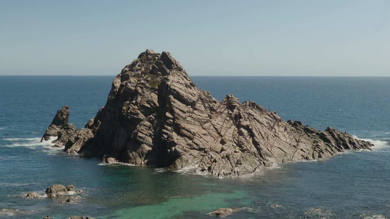 Close-up view of Sugar Loaf Rock, showcasing its rugged texture and unique shape against the coastal backdrop.