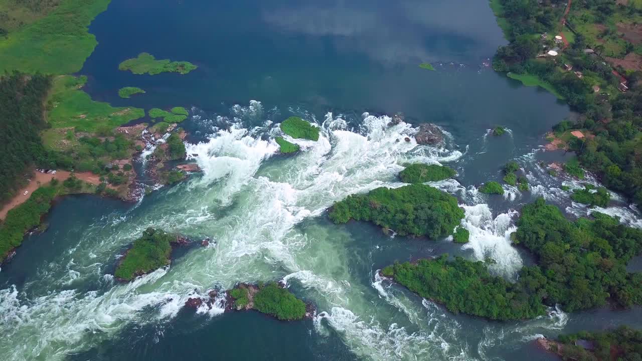 Drone pull out showcasing the majestic panorama of the River Nile as it flows through Uganda, Africa, creating breathtaking waterfalls and lush green islands, a testament to the raw beauty of nature