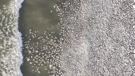 a partially frozen lake with ice patterns and open water, aerial view