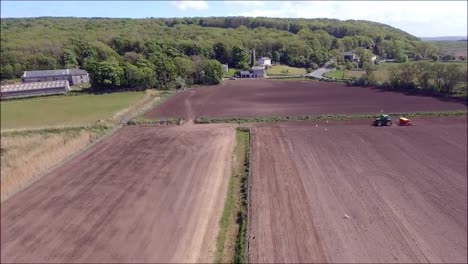 tractor ploughing field as birds fly around behind it