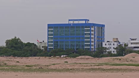 maritime rescue coordination center (mrcc) building with sand, trees and crows at varuna salai road, port trust officers quarters, sathya nagar, chennai, tamil nadu, india. day time, pan shot, 4k.