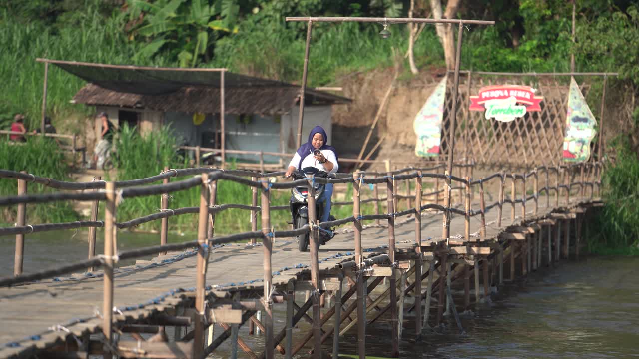 activities of rural people going to work using motorbikes across a bridge made of traditional wood. Big river, Progo river, Kulonprogo.