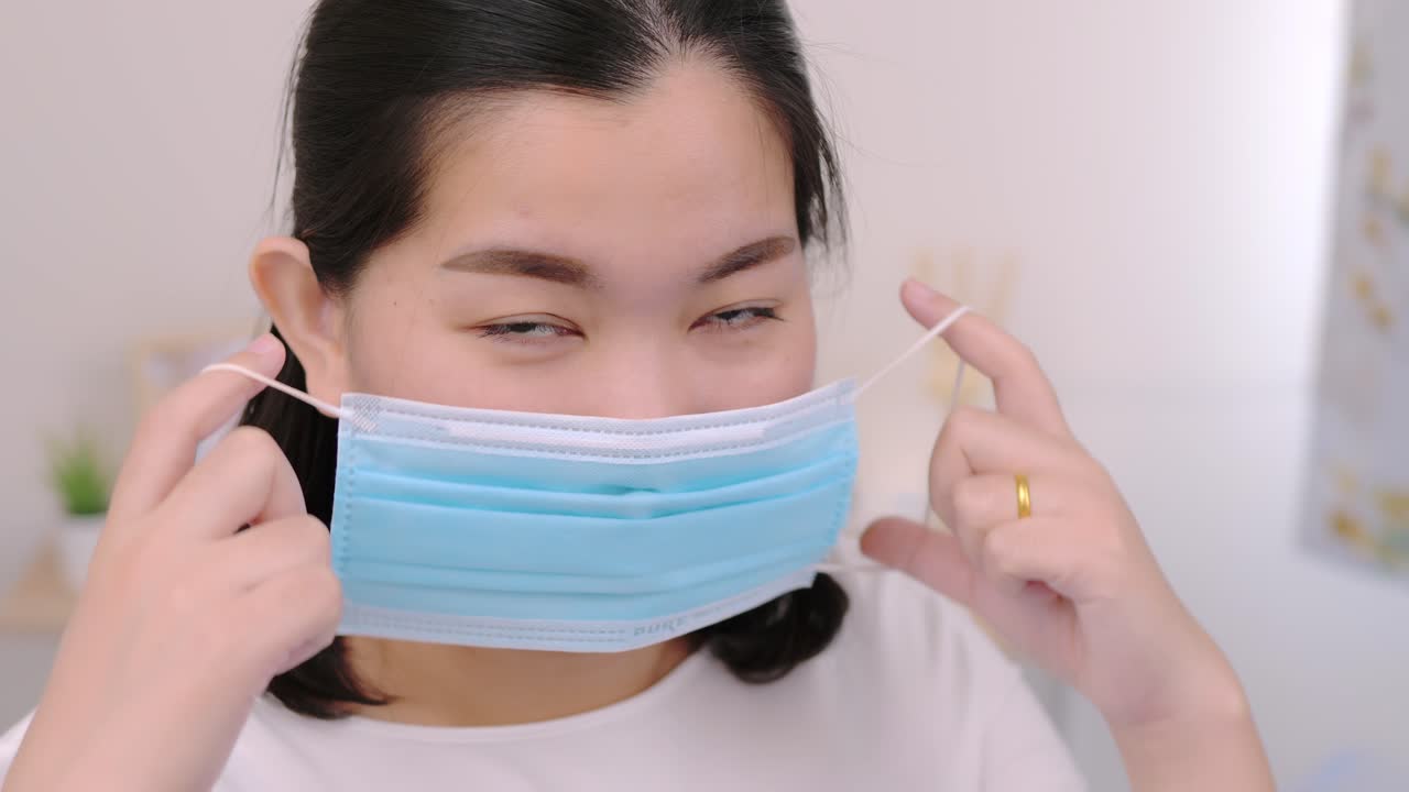 hermosa mujer asiática con una cámara con aspecto de máscara y estancia relajante en la cama en casa estilo de vida y concepto de placer