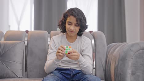 un niño indio enojado se frustra al no poder resolver el cubo de rubik