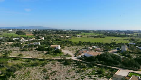 Drone-footage-reversing-to-the-side-over-fields-and-little-houses-on-Formentera