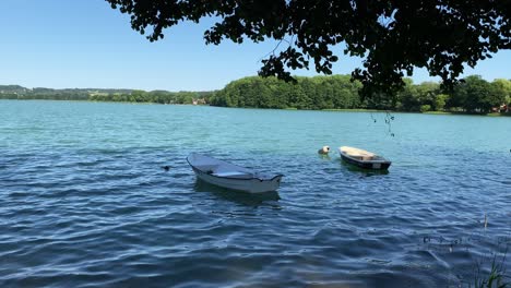 Static-shot-from-seashore-of-two-anchored-boats-on-lake-during-waves-on-lake-in-summer