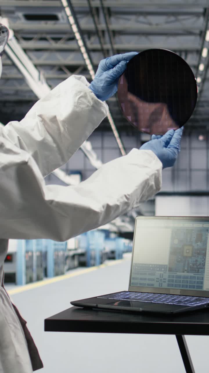 Vertical video Automated microchip foundry engineer assessing hardware fabrication with laptop