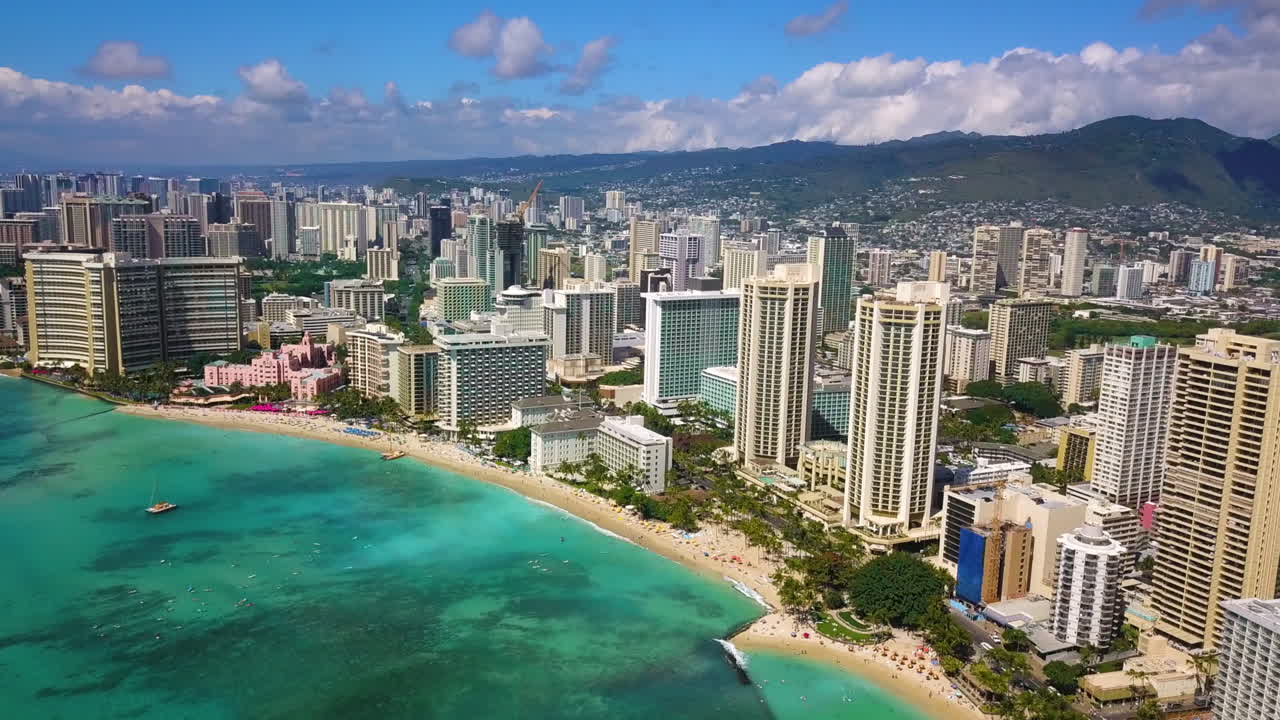 Aerial 4k shot of a seaside tropical city Oahu in Hawaii with a clear blue sea.