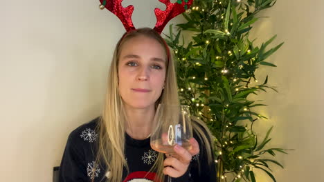 young woman on christmas video call watching someone open gift and talking to camera