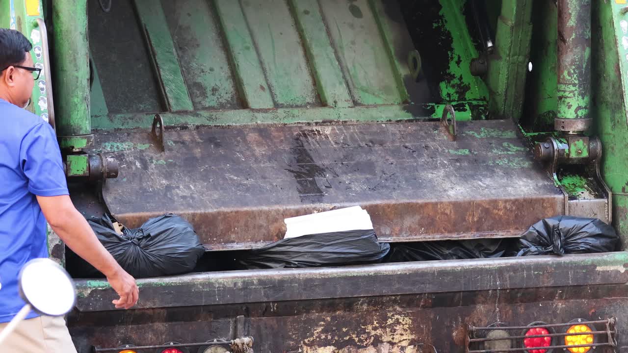 trabajador cargando bolsas de basura en un camión de basura