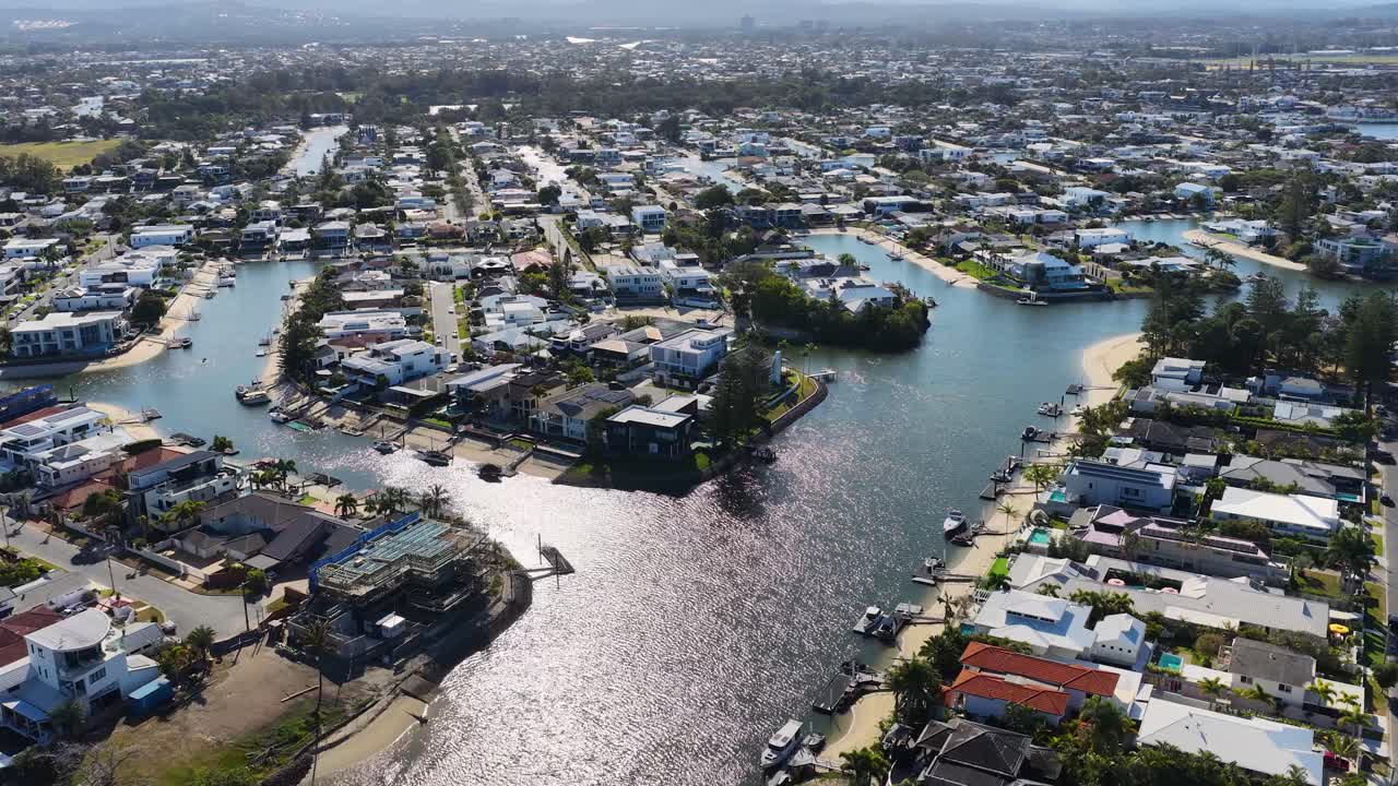 Drone glides above residential canal neighborhoods, sunny daylight, wide aerial perspective, smooth camera movement
