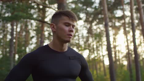 retrato de un apuesto hombre deportivo sonriendo y mirando a la cámara en el bosque