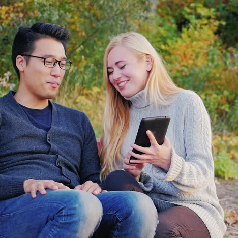 Friends-relax-in-the-park-and-use-a-tablet