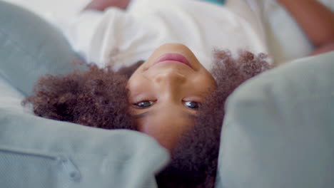 primer plano de la cara de una linda chica negra acostada en la cama y mirando a la cámara