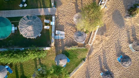 breathtaking view of drone flying over the shacks at the sandy beach and resort on a bright sunny day