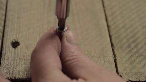 Hand using manual screwdriver to secure screw into wood-1