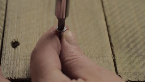 hand using manual screwdriver to secure screw into wood-1