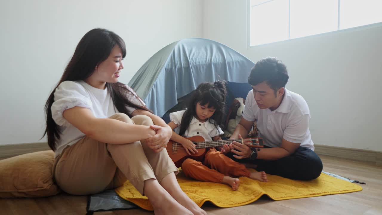 중국어 어린 소녀가 아버지와 함께 우쿨레를 배우고 있습니다.