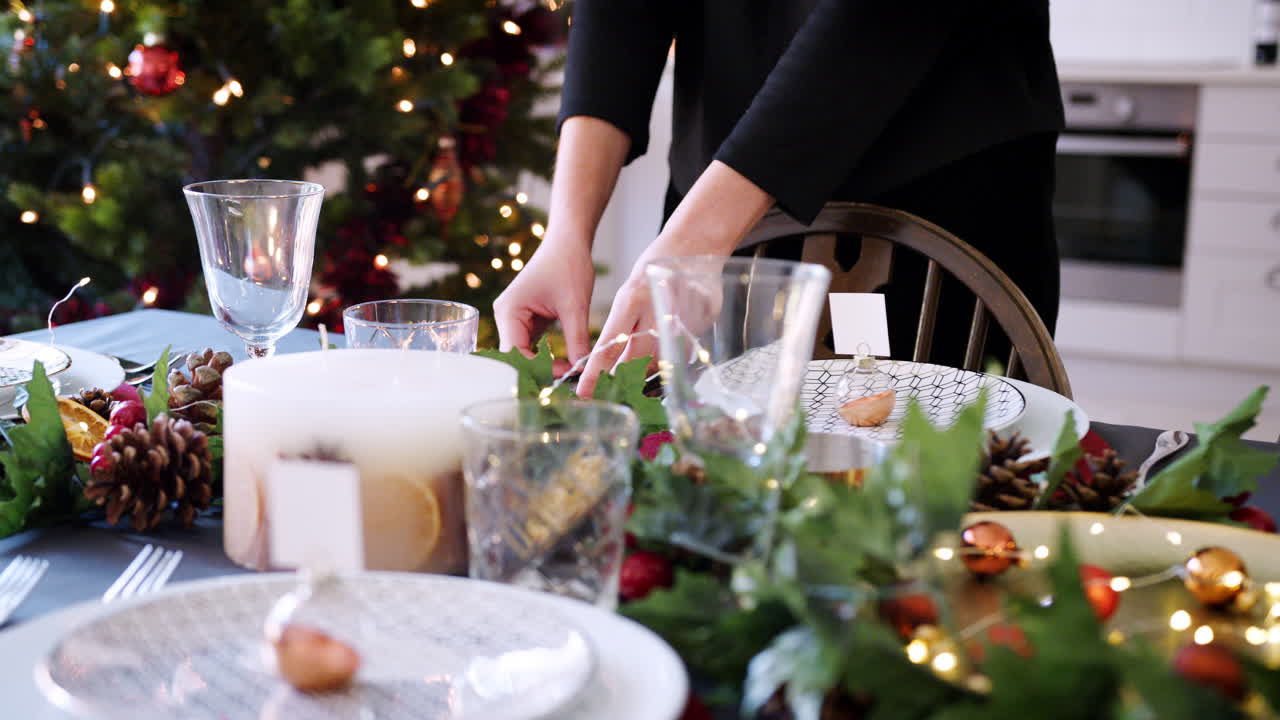 sección media de una mujer colocando cubiertos en una mesa de comedor decorada para la cena de navidad, enfoque selectivo