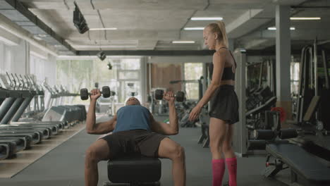 Vista-Frontal-De-Una-Monitora-Caucásica-Y-Un-Atlético-Afroamericano-En-El-Gimnasio.