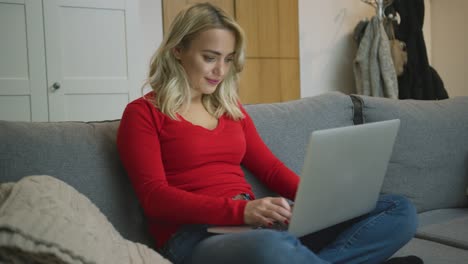 smiling woman using laptop on sofa