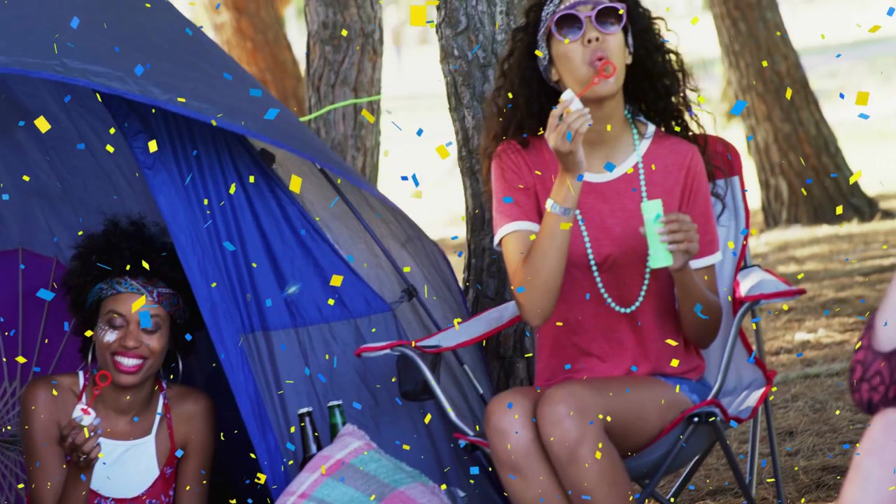 Vertical video: group in camp tent raising wands blowing bubbles relaxing, panning showing confetti
