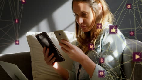 globes of digital icons spinning caucasian woman using smartphone and digital tablet at home