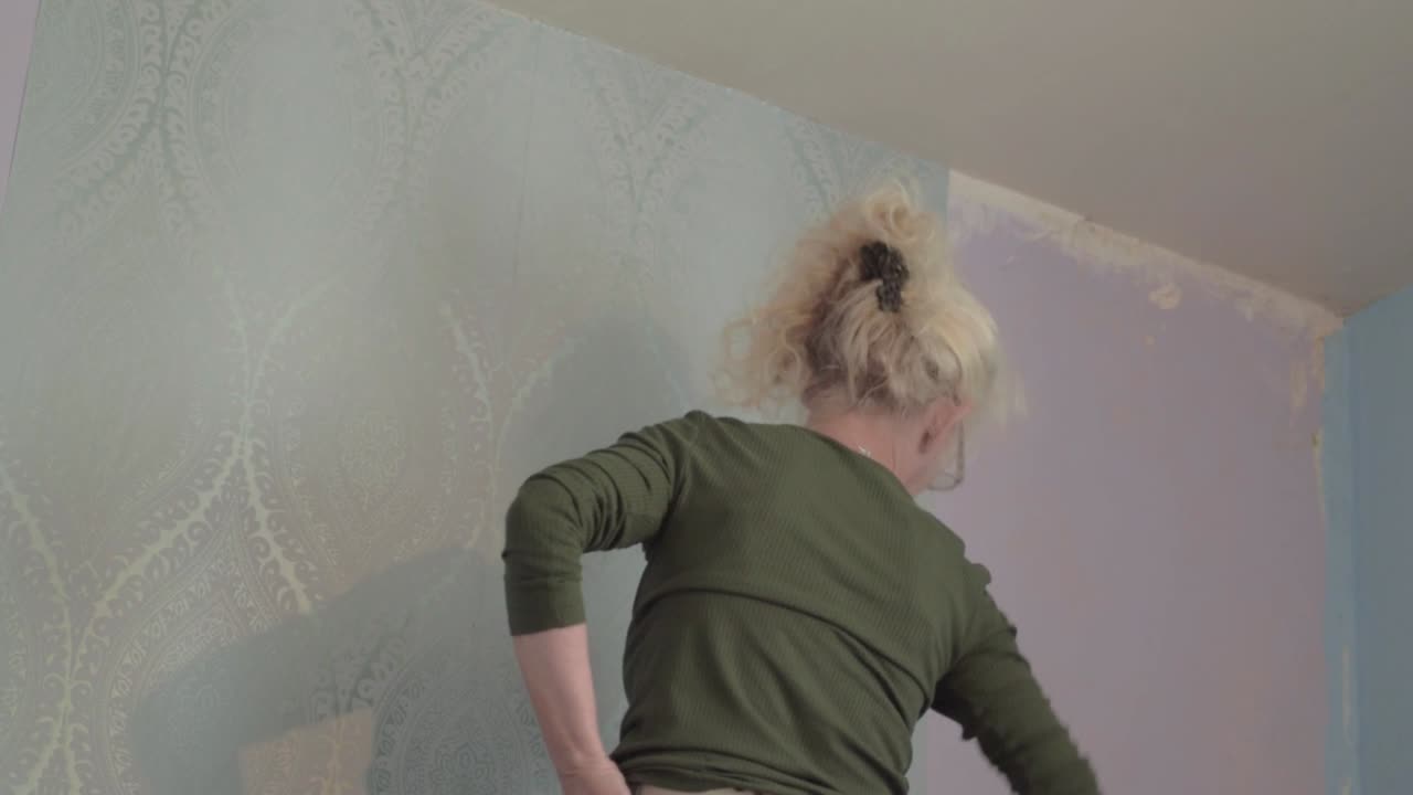 decorador de mulher pendurando papel de parede no quarto interior da casa