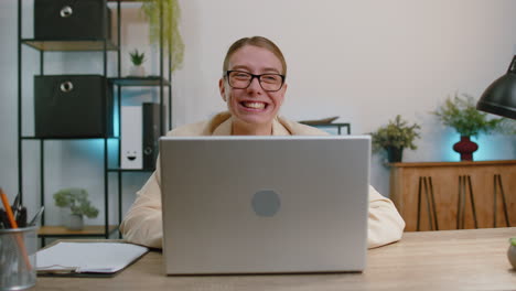 Businesswoman-hiding-behind-laptop-computer,-making-funny-face-fooling-around-putting-his-tongue-out