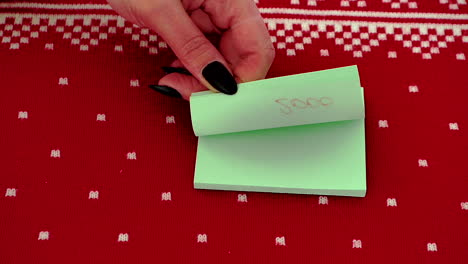 Hojear-A-Mano-Notas-Post-it-Con-Cambio-De-Año-Contra-Fondo-De-Diseño-Rojo