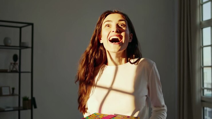 A joyful woman holding a colorful gift box, captured in a close-up angle