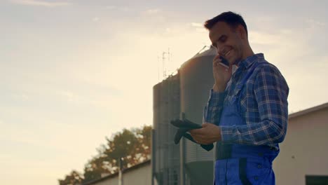 joven agricultor hablando por teléfono móvil en la granja