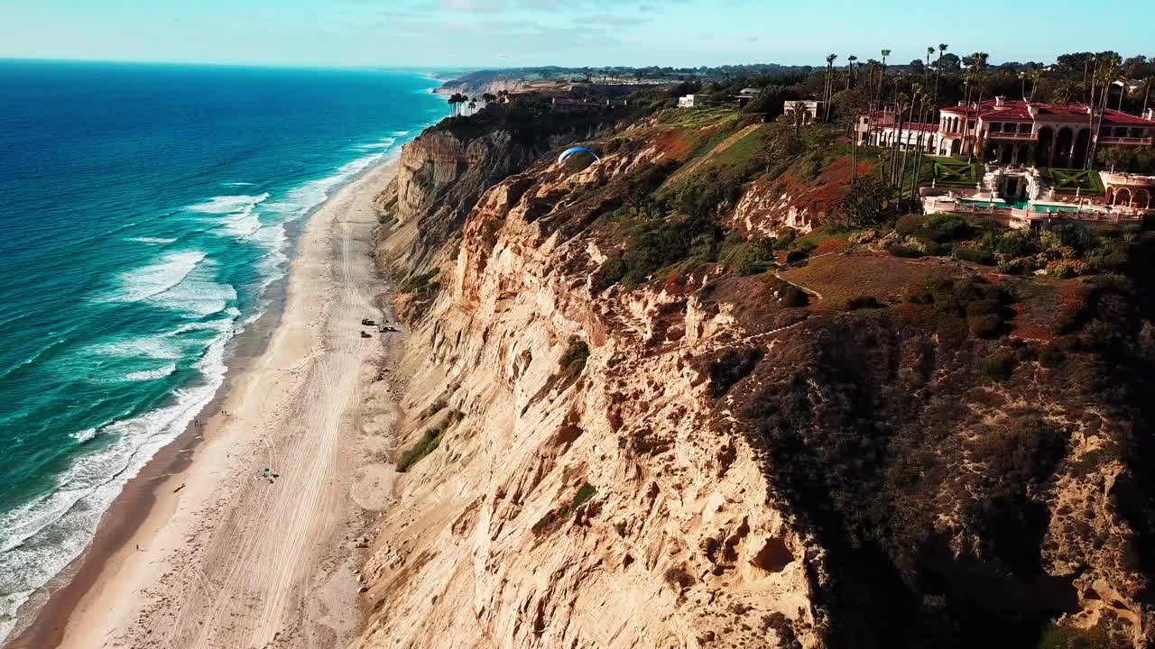 깨끗한 해안선 위의 절벽을 따라 활공하는 행글라이더와 패러글라이더