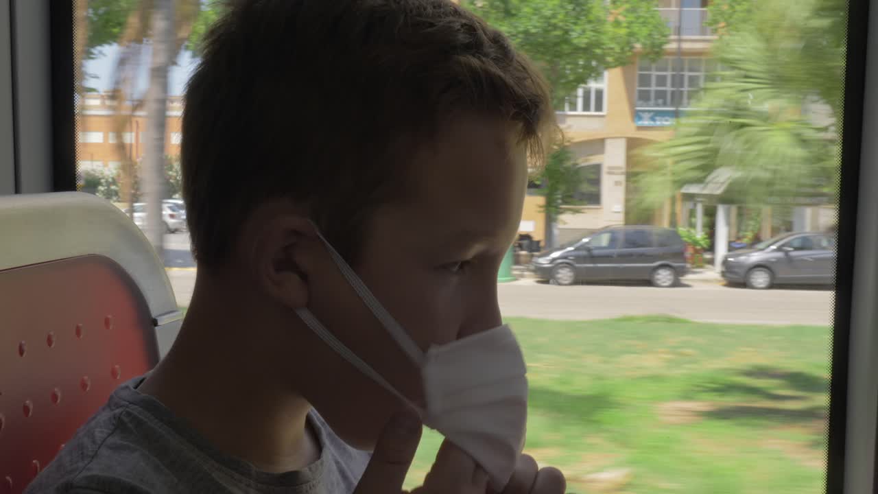 얼굴 마스크를 입은 배고픈 아이가 버스에서 김을 먹고 있다