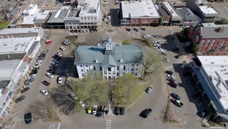 Lafayette-County-historic-courthouse-in-Oxford,-Mississippi-with-cars-driving-in-town-square-and-drone-video-stable-close-up