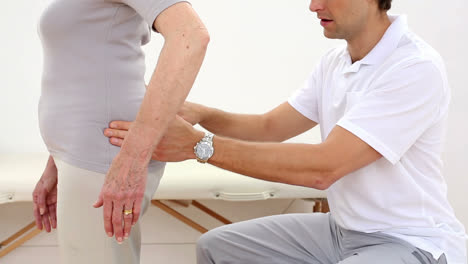 Physiotherapist-touching-senior-patients-hips