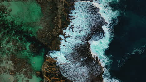 Crashing-blue-waves-spreading-on-rocky-coast,-aerial-boom-up,-Hawaii