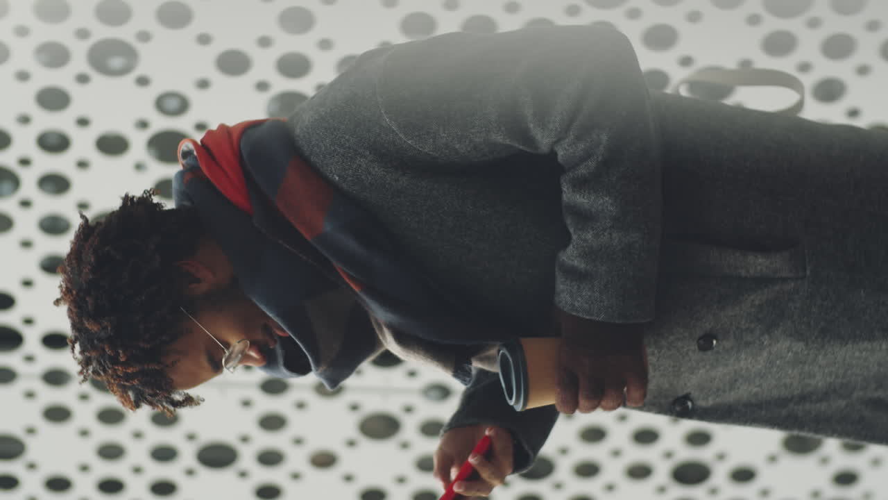Man walking in a city, using his phone, looking down, with a coffee cup