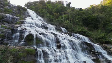 aerial slowly ascends wispy mae ya waterfall in lush thailand jungle