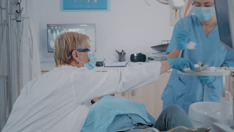 stomatologist and nurse doing extraction procedure on patient