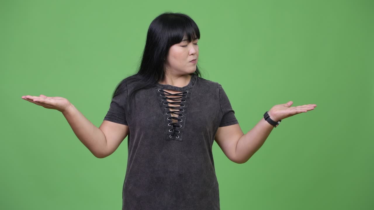 Beautiful overweight Asian woman comparing something