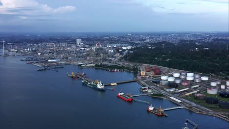 Rising-view-of-Docked-Oil-Tanker-Ships-and-Pertamina-Oil-Refinery-in-the-background---Port-of-Balikpapan-City,-Indonesia