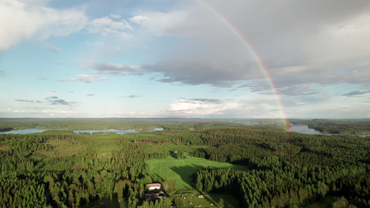 impresionante arco iris sobre hermoso paisaje sereno de bosques y lagos en finlandia, casas de granja en primer plano, cerca de kuopio, cámara empujando en