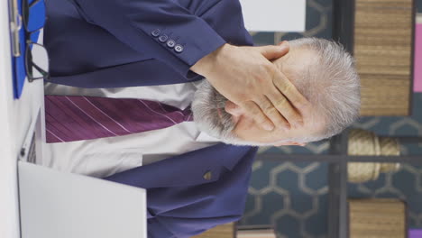 Vertical video of Sleepy old businessman yawns looking at camera.