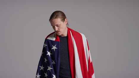 retrato de estudio de un hombre envuelto en la bandera estadounidense celebrando el 4 de julio, día de la independencia.